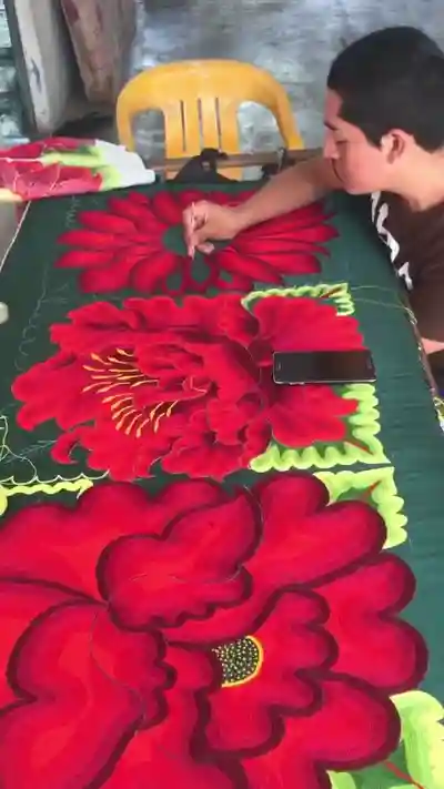 Artesana creando diseño floral bordado sobre tela
