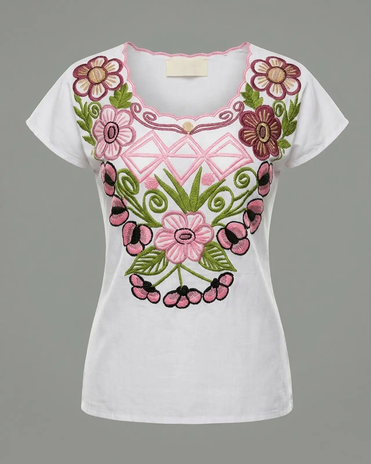 Blusas blancas con bordados florales de colores sobre mesa de madera